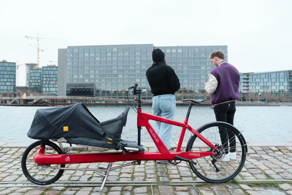 A young man and woman chatting by water with cargo bike VeloSled Anna on Islands Brygge in Copenhagen