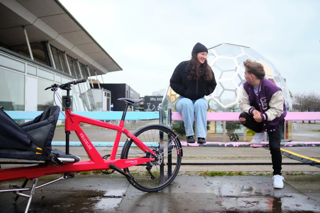 A young man and woman hanging out at Islands Brygge with their cargo bike VeloSled Anna